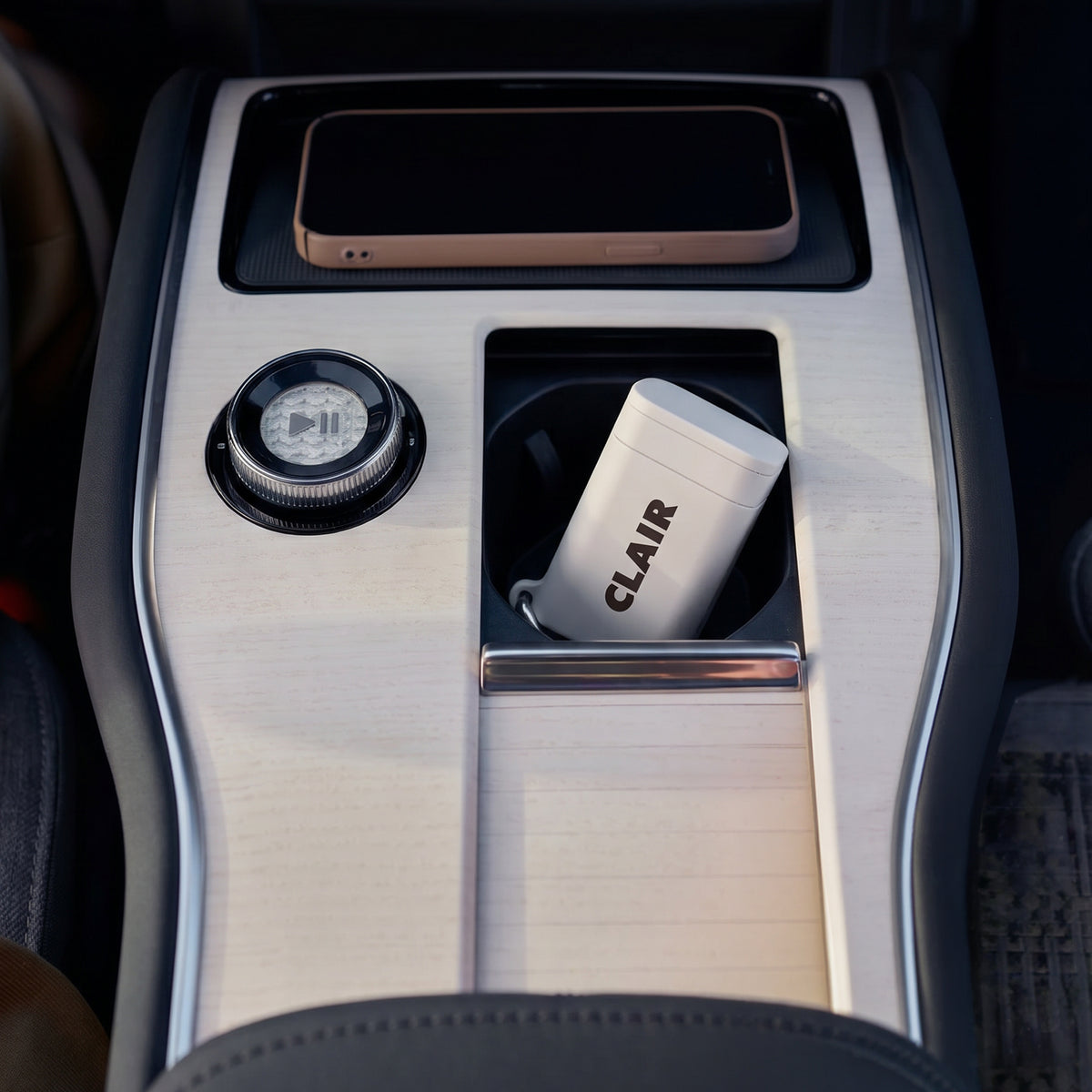 CLAIR case in Cloud standing in a car's center-console cup holder below a phone on the charging pad